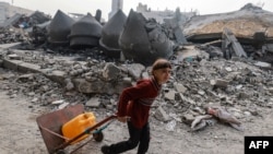 A child carries a jerrycan of water as he walks in front of the Al-Faruq mosque, leveled by Israeli bombardment in Rafah in the southern Gaza Strip on a foggy day, Feb. 25, 2024.